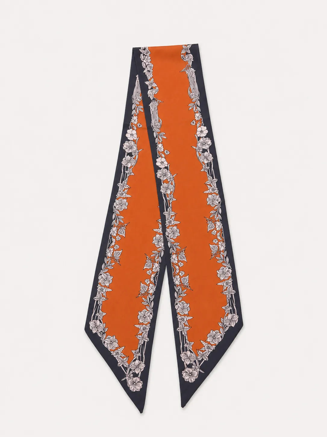 A product flat lay of a vibrant burnt orange satin skinny scarf with an elegant floral and ornamental border design.