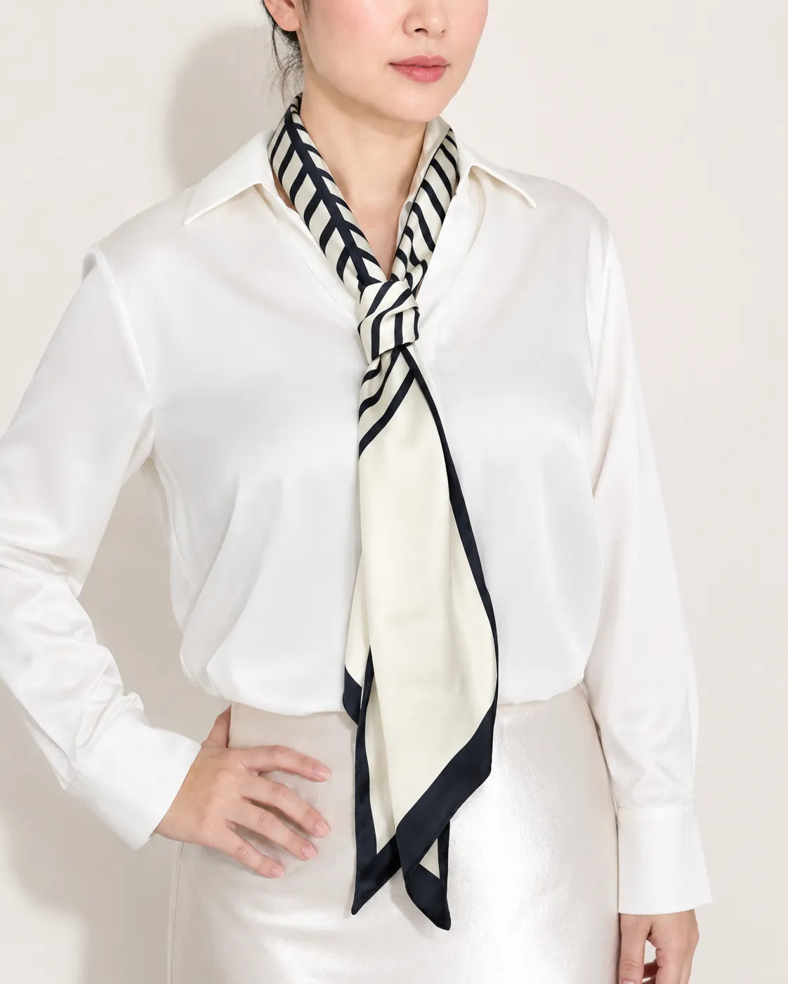 Close-up of a woman in a crisp white shirt wearing an ivory and black color-block satin twilly scarf tied in a neat knot at the front.