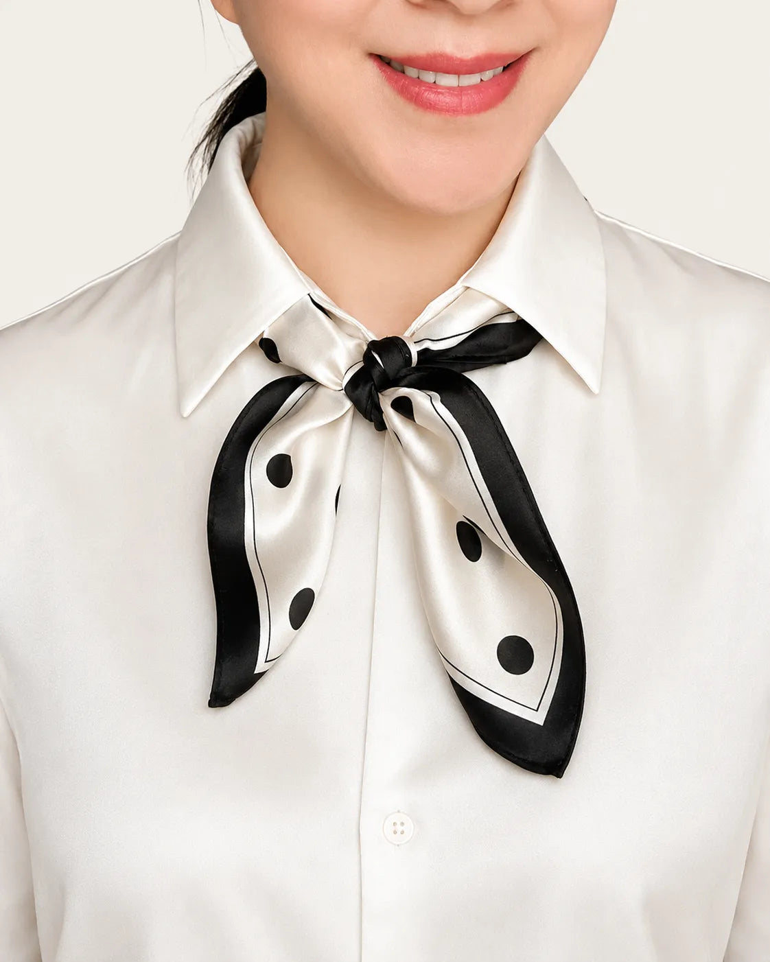 YANOVA premium 21 × 21 in (53 × 53 cm) 100% Mulberry silk square scarf in black and white polka dot pattern, styled as an elegant neck bow with a white blouse.